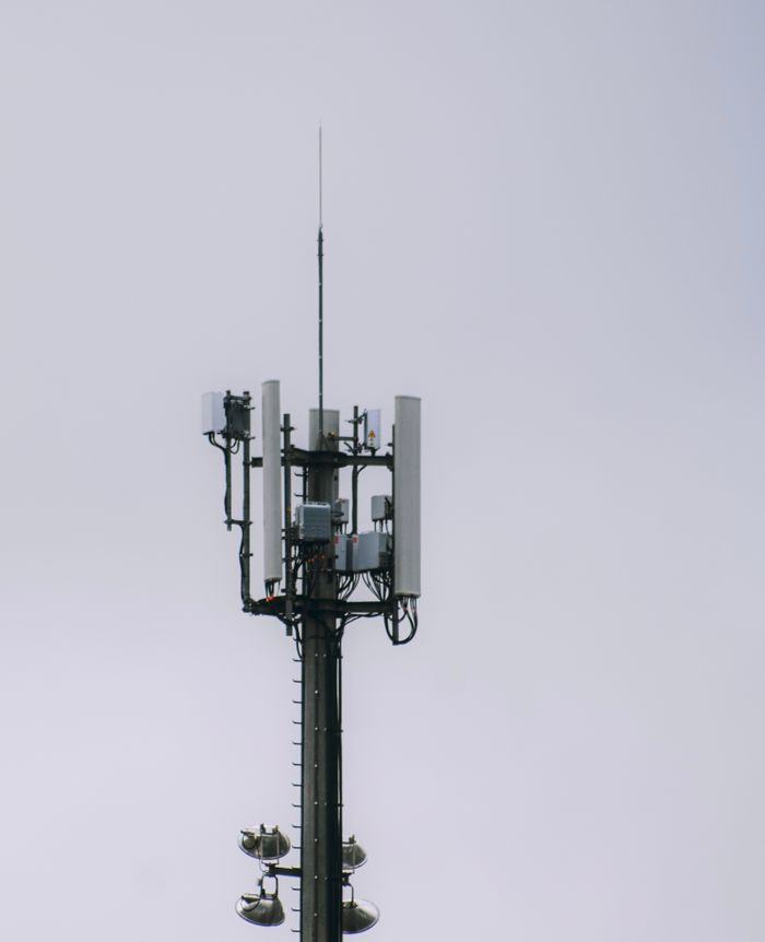 A modern telecommunication tower with antennas and equipment set against a grey sky, showcasing technology and connectivity.
