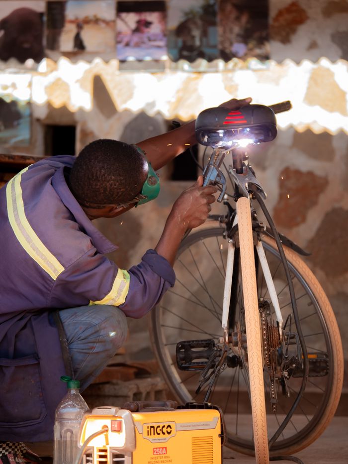Skilled mechanic welds bicycle in a workshop, showcasing craft and precision.