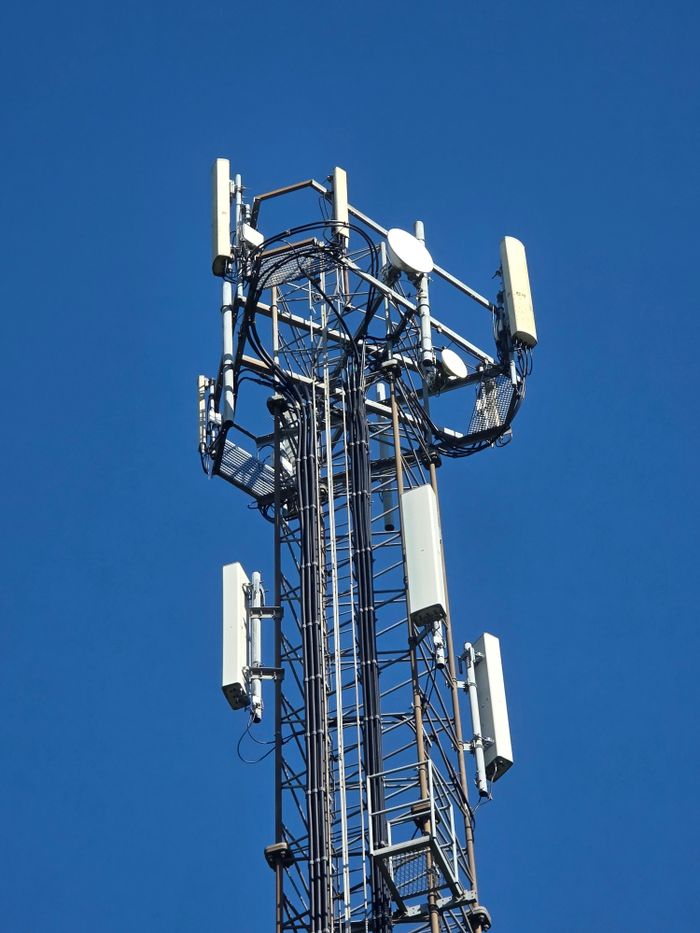 Close-up of a telecom tower under a clear blue sky, emphasizing connectivity.