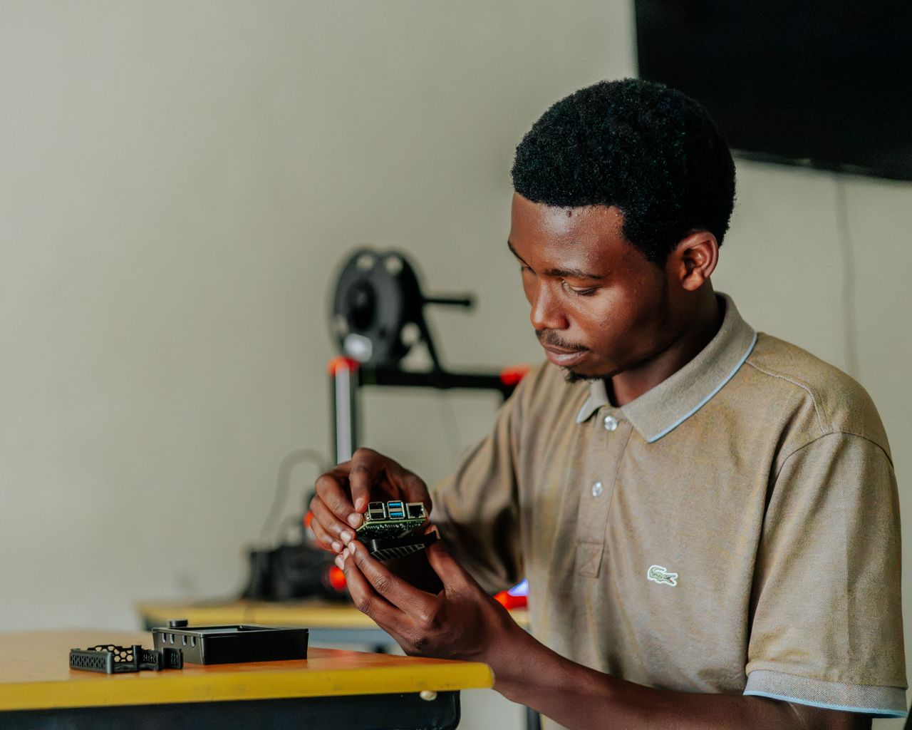 Focused man assembling an electronic circuit board at a desk, highlighting innovative technology and concentration.